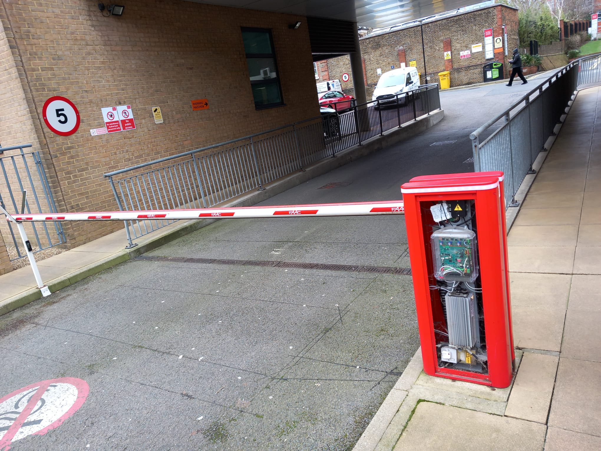 Car park barrier with control cabinet open for repair.